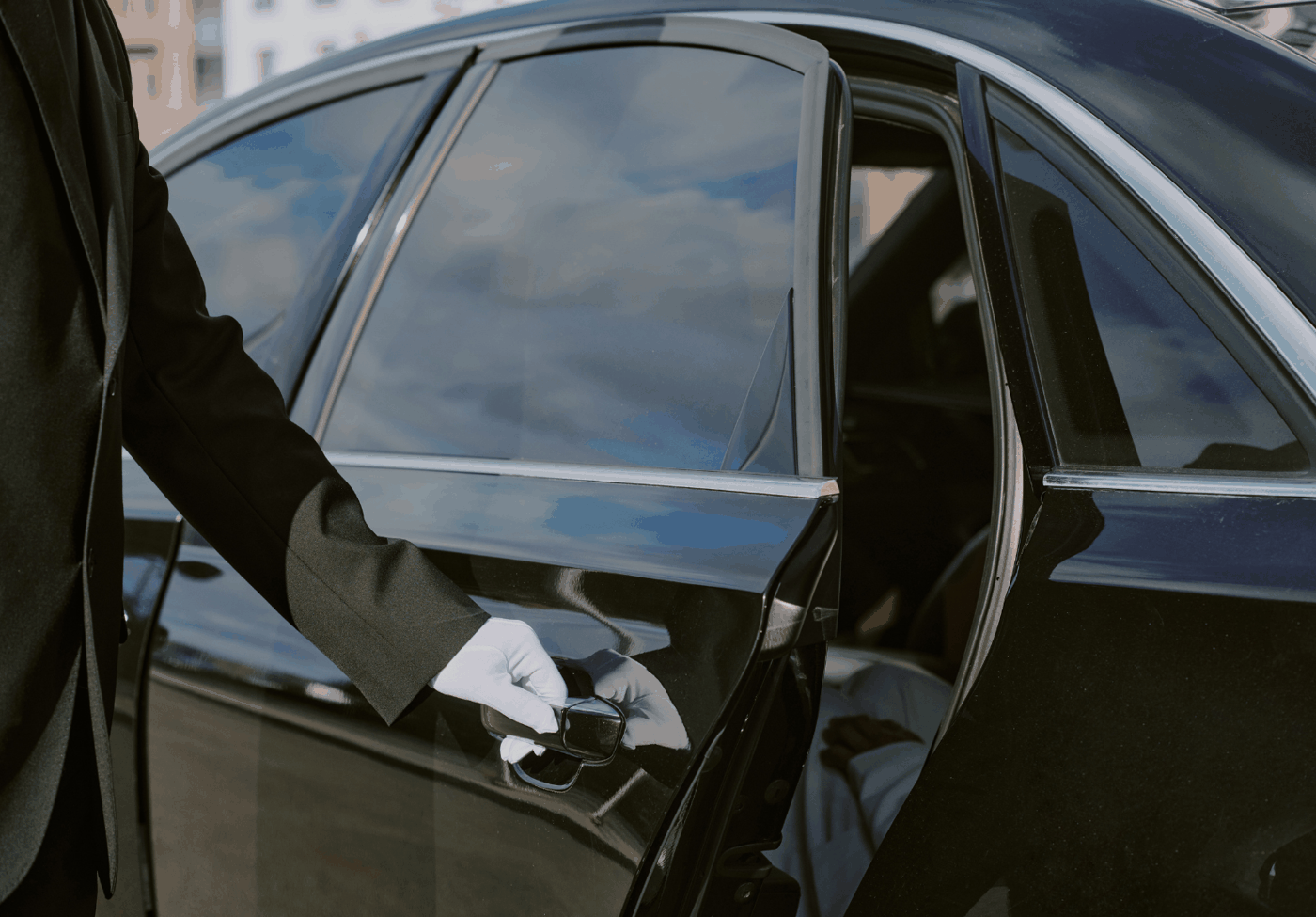 A driver opening the door for an executive about to exit a black car